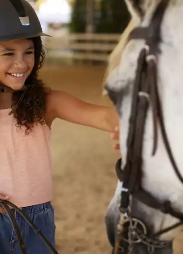 Une enfant caressant un poney